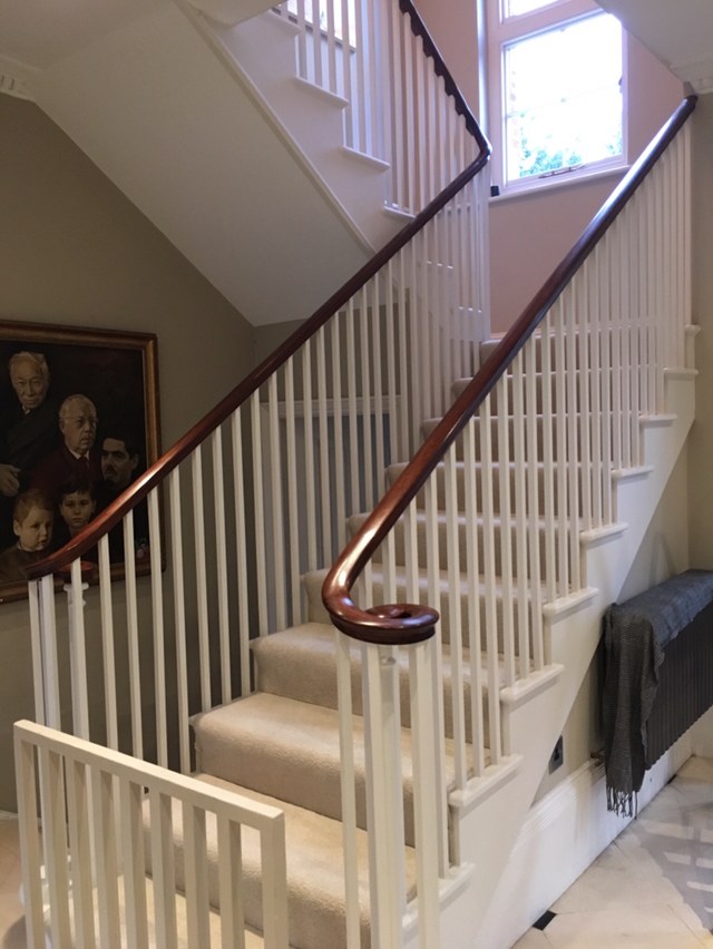 Restored staircase with polished mahogany handrail and painted spindles